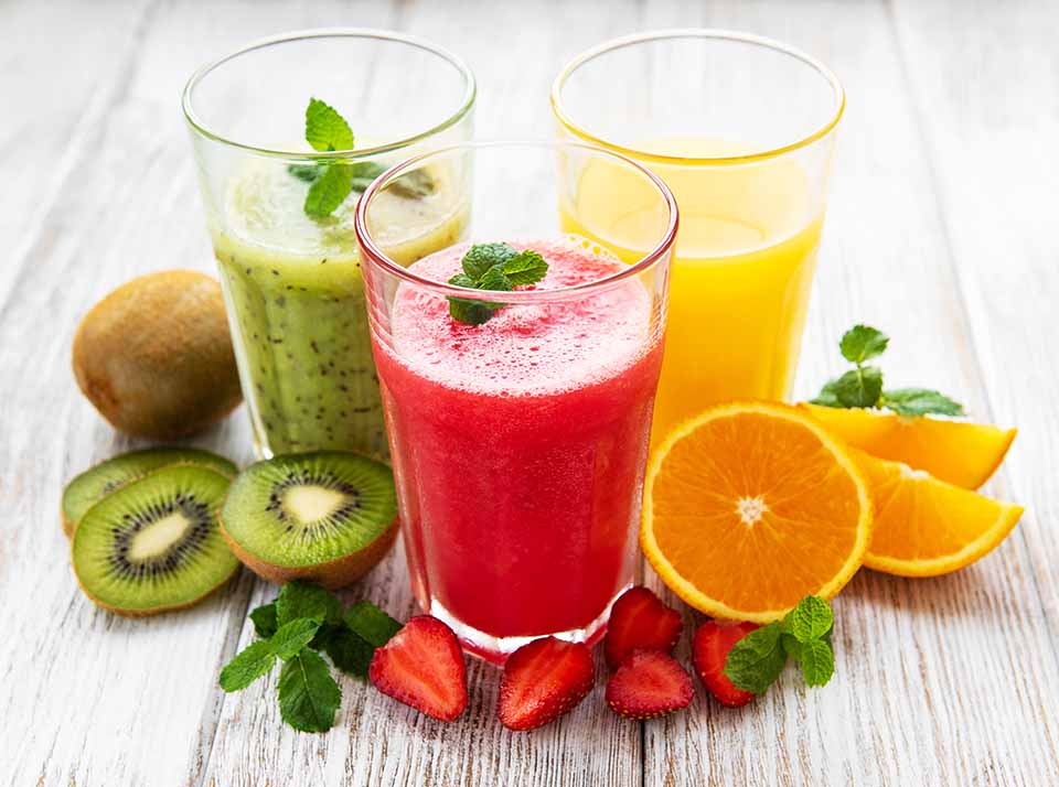 Fruit smoothies with fruit surrounding them